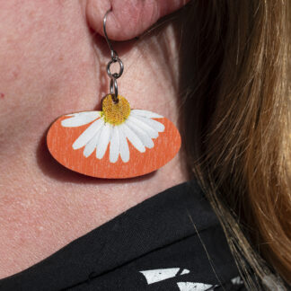 Koivuvaneriset päivänkakkara-korvakorut korvassa